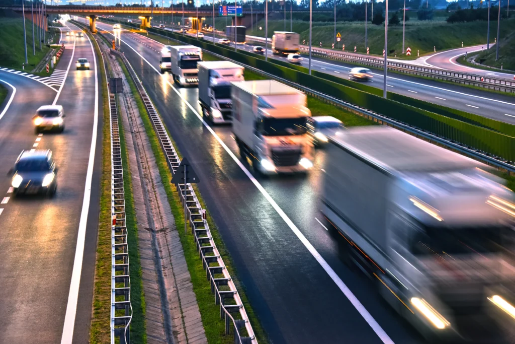 高速道路を走行する複数のトラックと車両の様子を捉えた物流イメージ